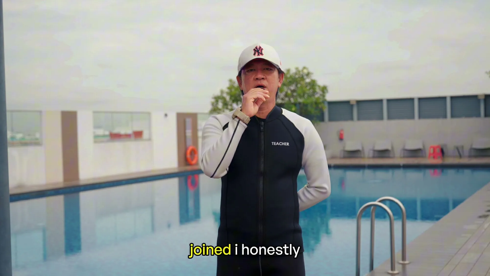 Teacher Ken, in a cap, speaking by a condo pool